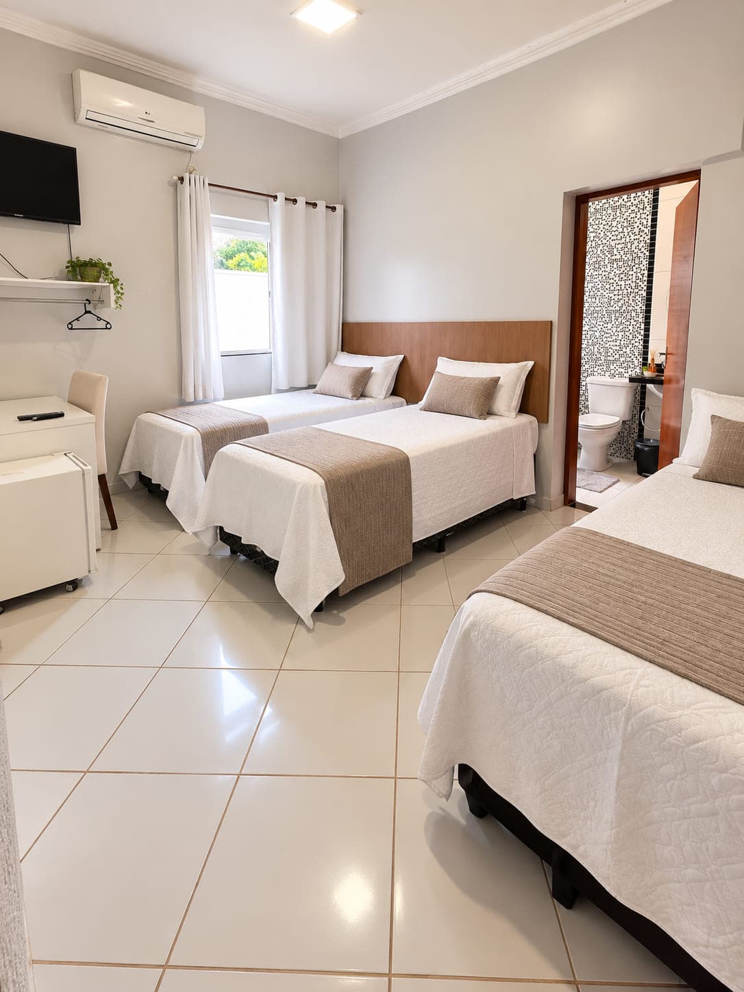 Quarto triplo do Garden Hotel com três camas, ar-condicionado e banheiro privativo